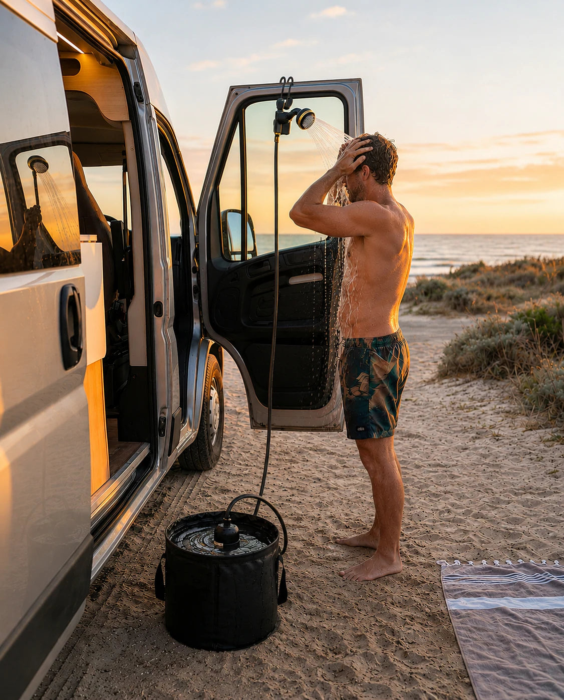 Douche portable AquaNomad utilisée près d'un van à la plage
